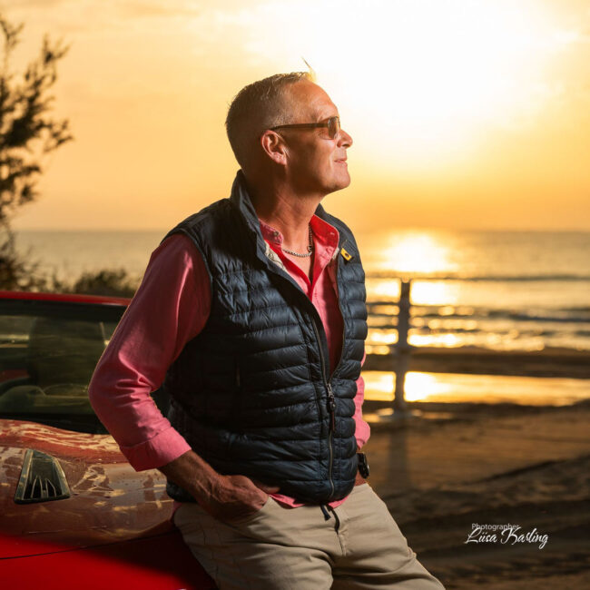 A man with his car on a sunrice at the beach